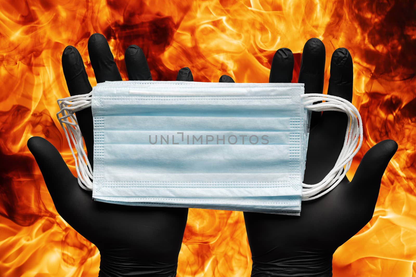 Doctor holding lot medical face masks in hands in black protective gloves on background flames of strong red fire by Alexander-Piragis