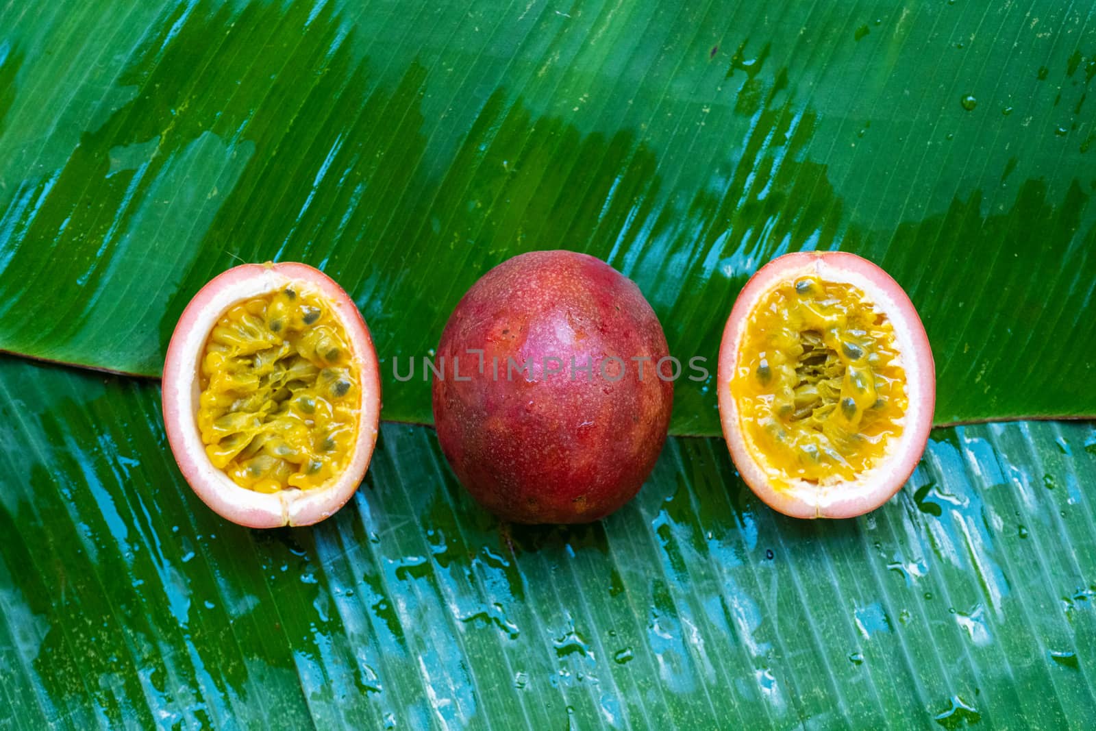 Ripe passion fruit, on a wet banana leaf. Vitamins, fruits, healthy foods.