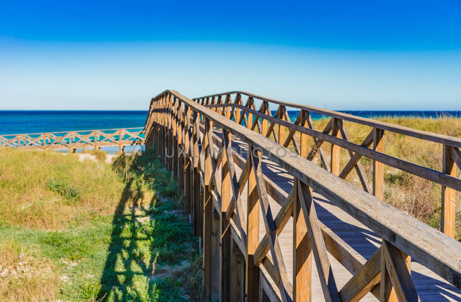 Wooden footbridge over the sand dunes to the beach of Alcudia bay on Majorca, Spain Mediterranean Sea