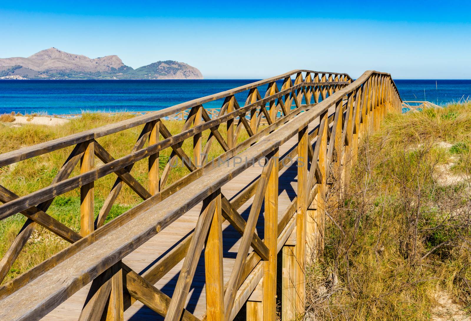 Wooden footbridge over sand dunes on Majorca island at the bay of Alcudia, Spain
