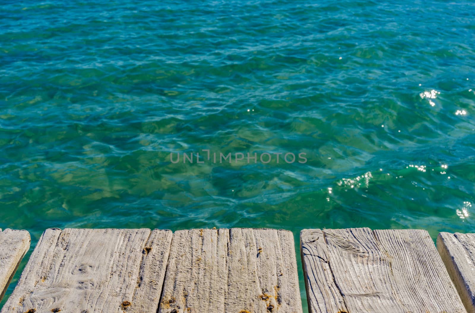 Wooden jetty on blue sea water background