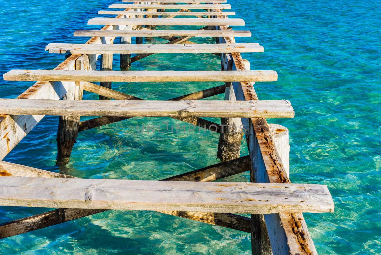 Close-up of damaged wooden jetty with blue sea water