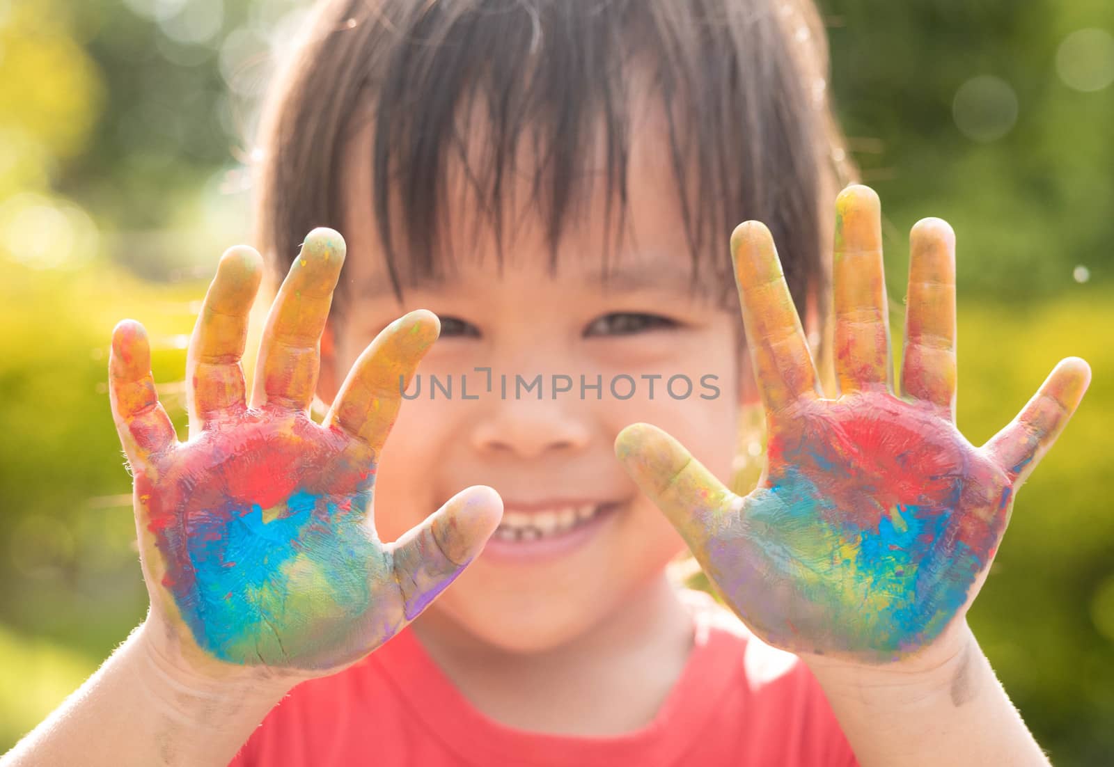 Cheerful little child girl with hands painted in colorful paints by TEERASAK