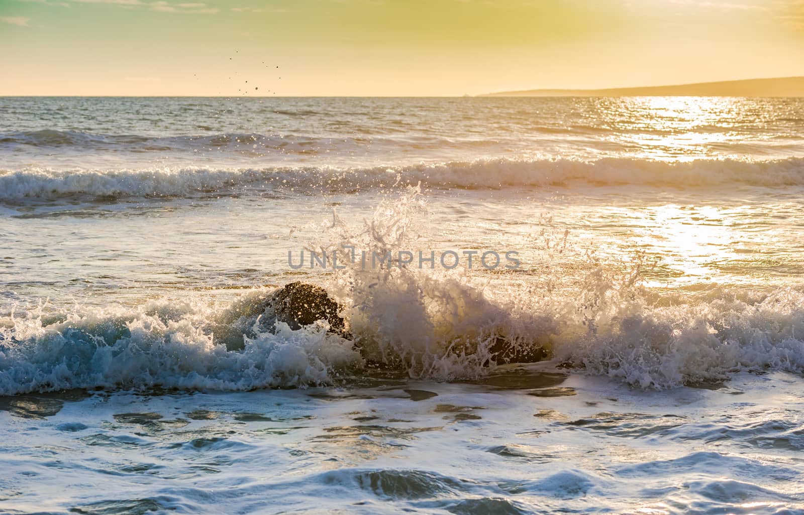 Beach surf wave breaking on rocky coast