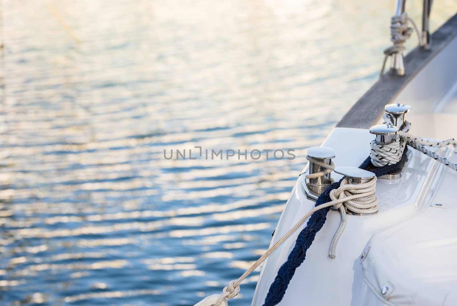 Close-up of yacht boat deck with coiled mooring rope on bollard