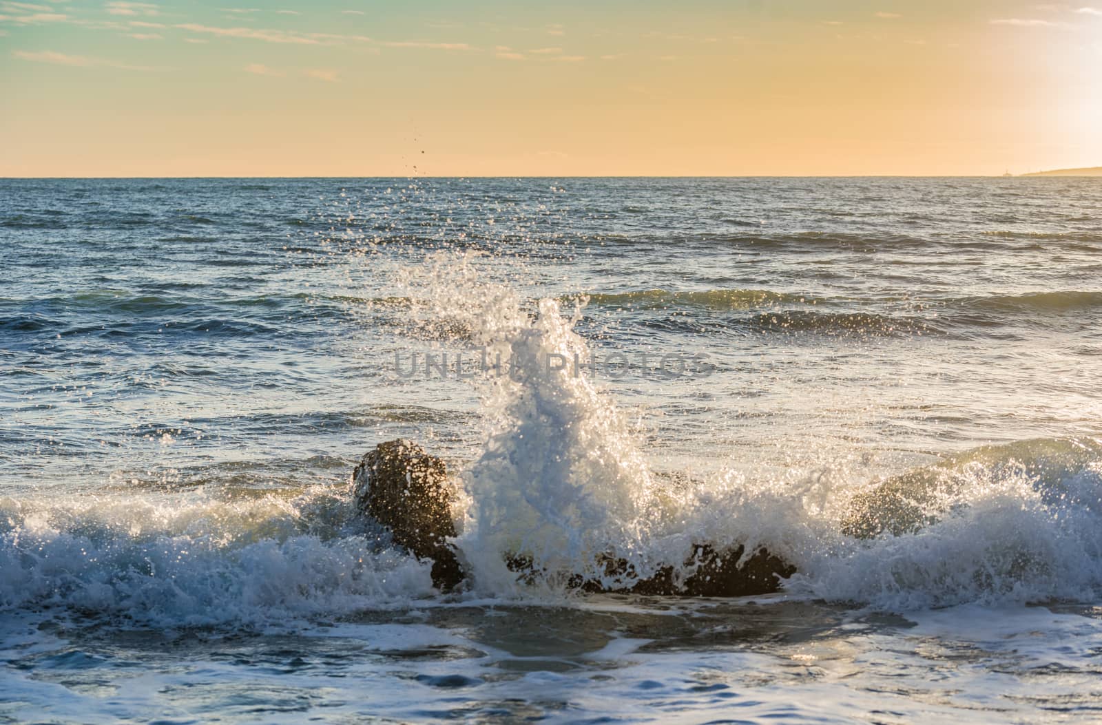 Beach surf wave breaking on rocky coast