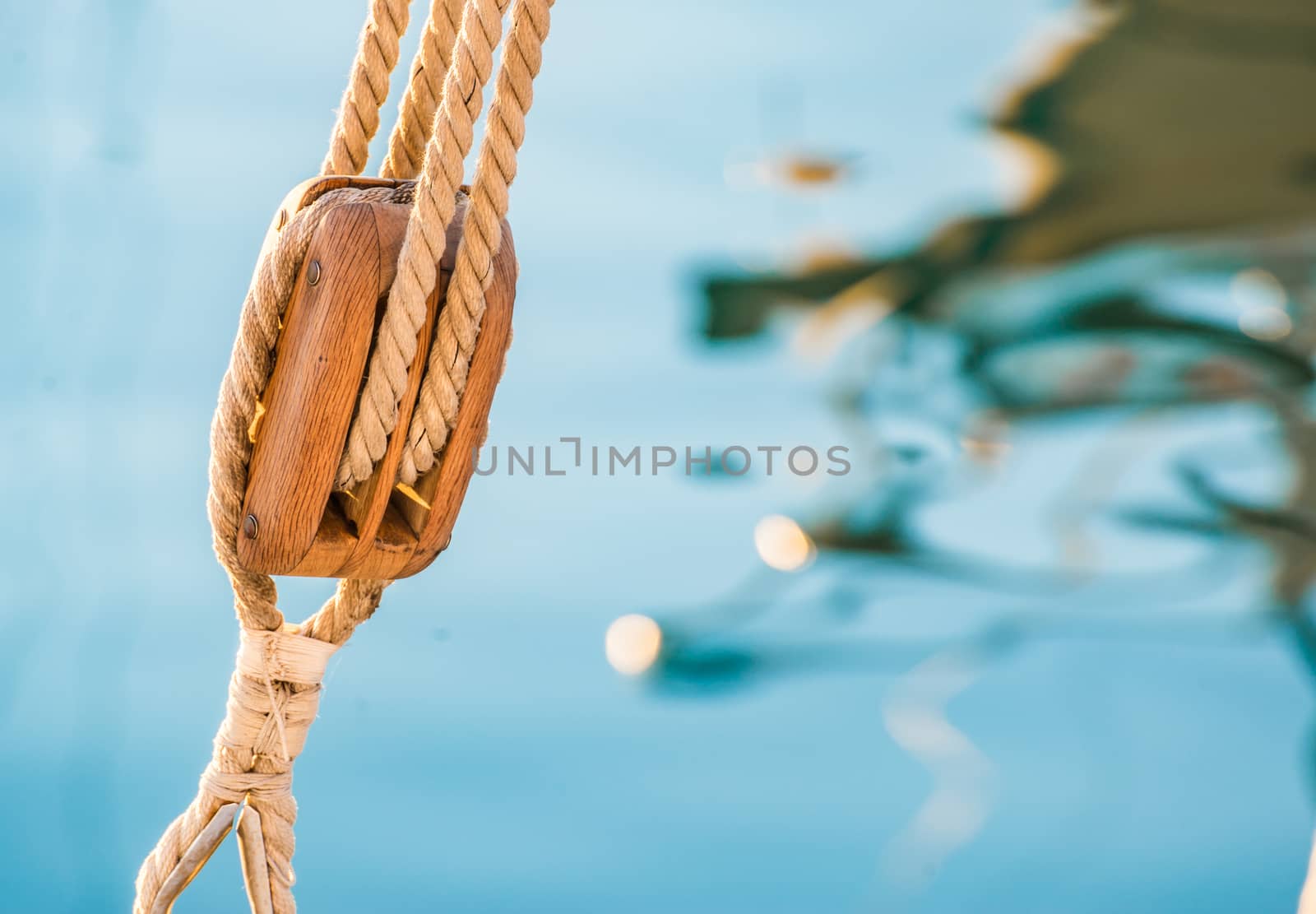 Nautical pulley with ropes of a classic sailing boat and blue sea water background