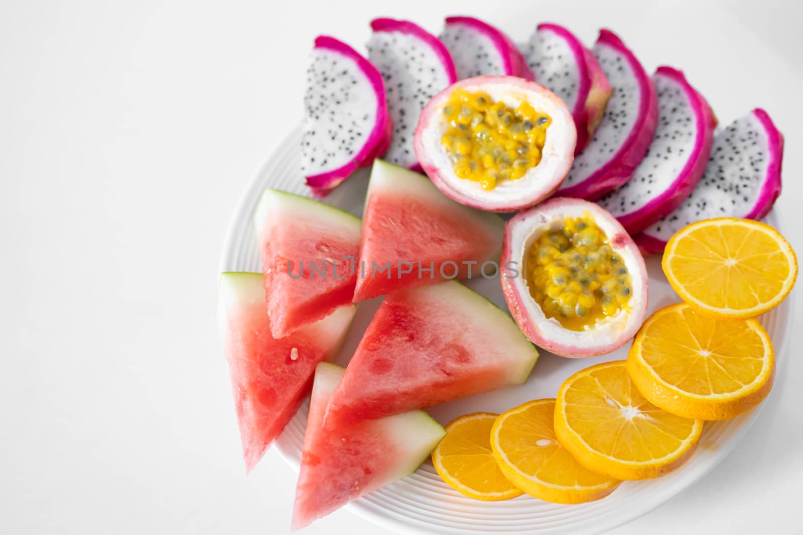 White plate of sliced fruit. Fresh fruits and vitamins. Still life colored summer fruits