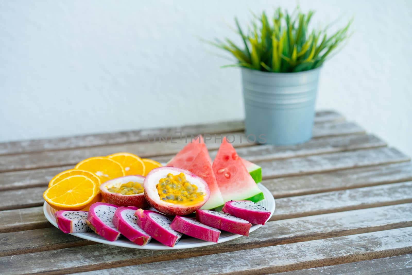 White plate of sliced fruit. Fresh fruits and vitamins. Still life colored summer fruits