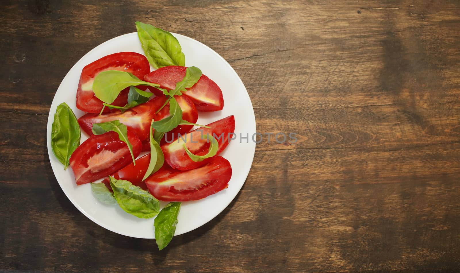 Sliced tomatoes with lettuce on a white plate. Healthy eating concept by selinsmo