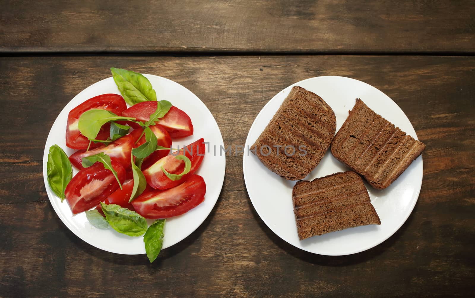 Sliced tomatoes with lettuce on a white plate. Fresh bread toast. Healthy eating concept by selinsmo
