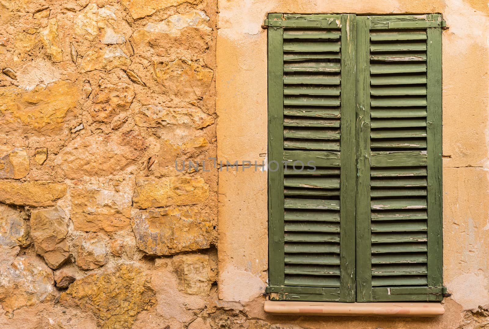Detail view of green closed wooden window shutters and rustic wall