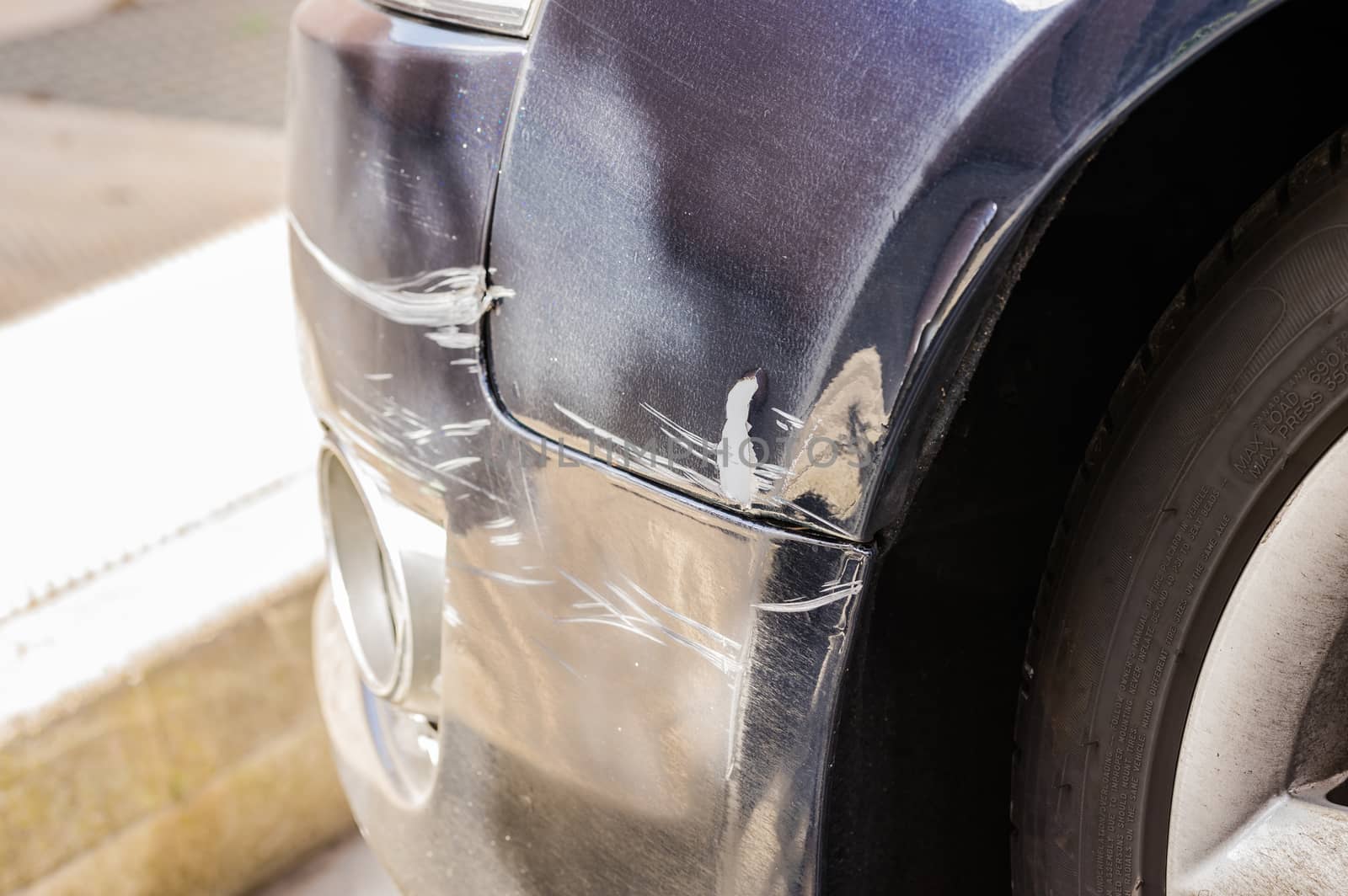 Close- up of damaged black colored car bumper and fender
