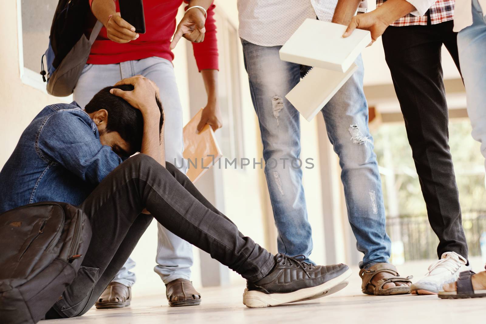 Teenage Boy Being Bullied At School, covered his face - group of students threatening to hit classmate or junior at university - Concept of teasing, bulling or warning at college campus. by lakshmiprasad.maski@gmai.com
