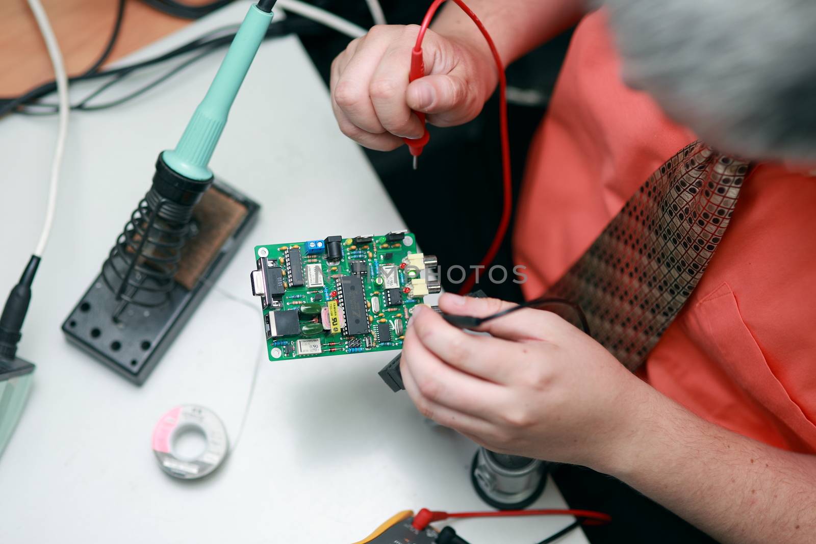 Hands of a man are engaged in the repair of electronics. Services, Manual assembly of the soldering circuit board. by selinsmo