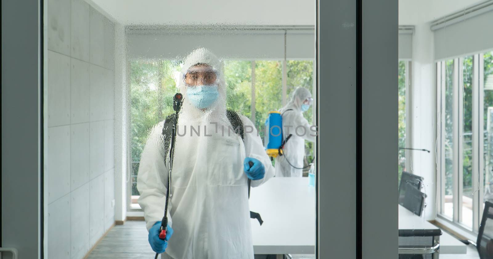 Professional  male worker In protective clothing and masks are spraying disinfectants, cleaning, controlling virus and bacteria in the contaminated area After the spread of coronavirus or COVID-19