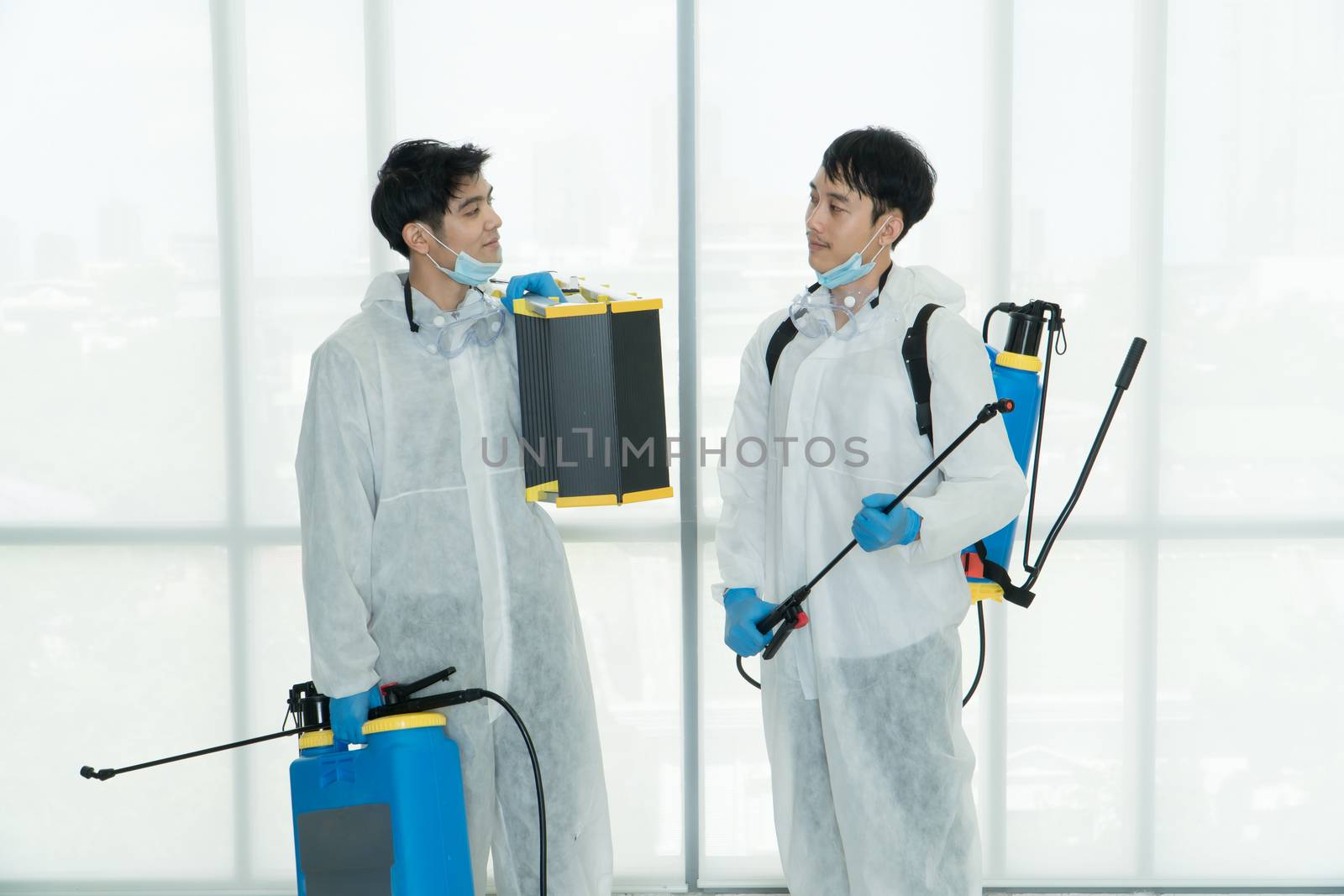 Professional  male worker In protective clothing and masks are spraying disinfectants, cleaning, controlling virus and bacteria in the contaminated area After the spread of coronavirus or COVID-19