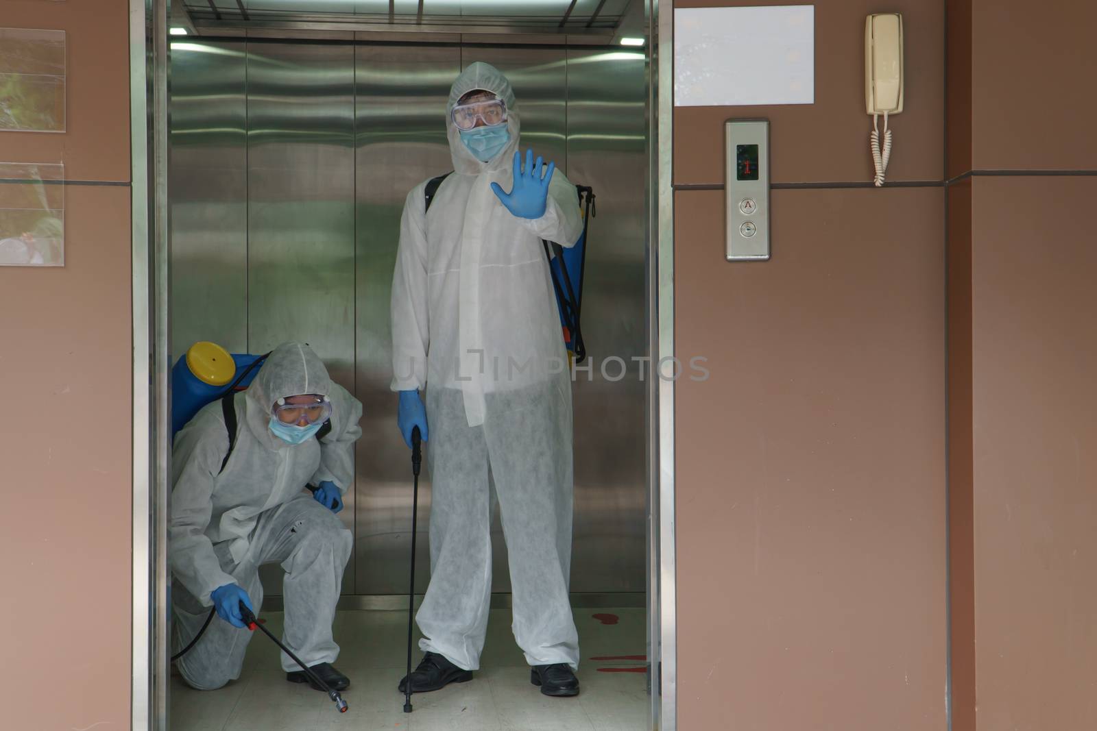 Professional male workers in protective clothing and masks are spraying disinfectants, cleaning, controlling the virus, and bacteria in contaminated areas. Specialist Show hand to stop coronavirus