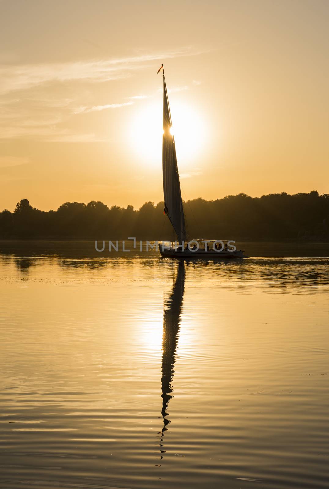 Traditional egyptian felluca sailing boat on river Nile in silhouette at dusk sunset