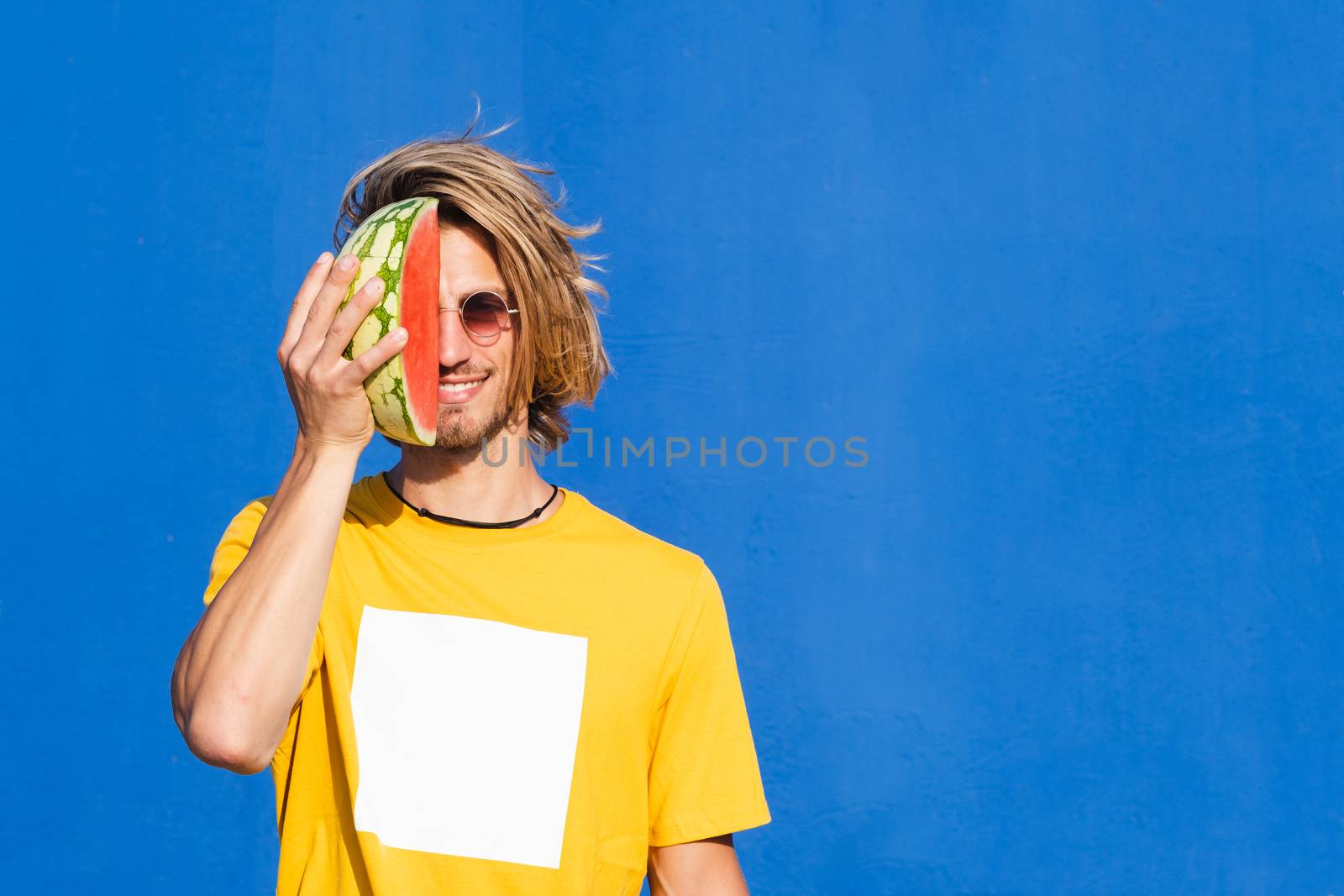 Young man with long blond hair with watermelon by Dumblinfilms