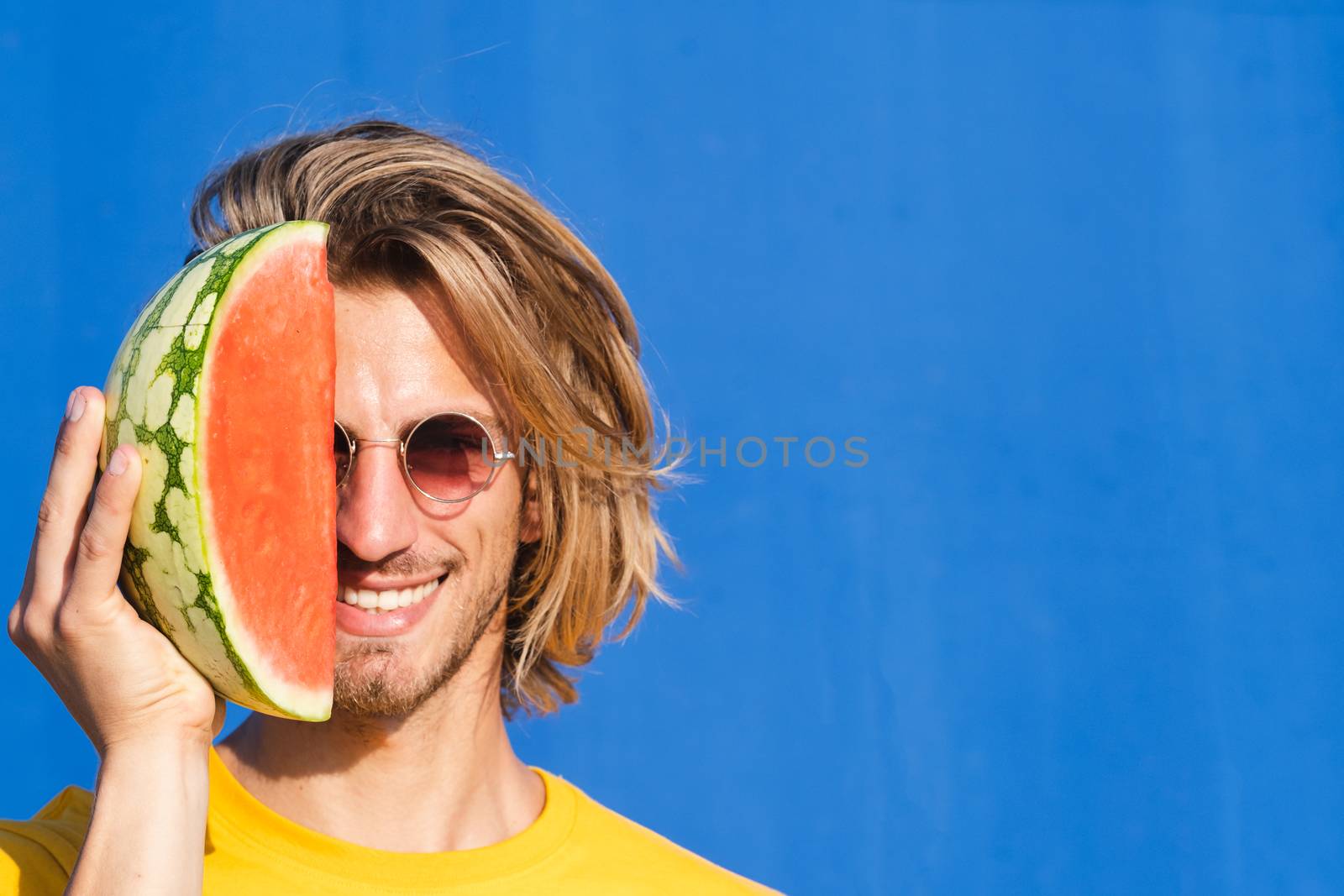 Young man with long blond hair with watermelon by Dumblinfilms