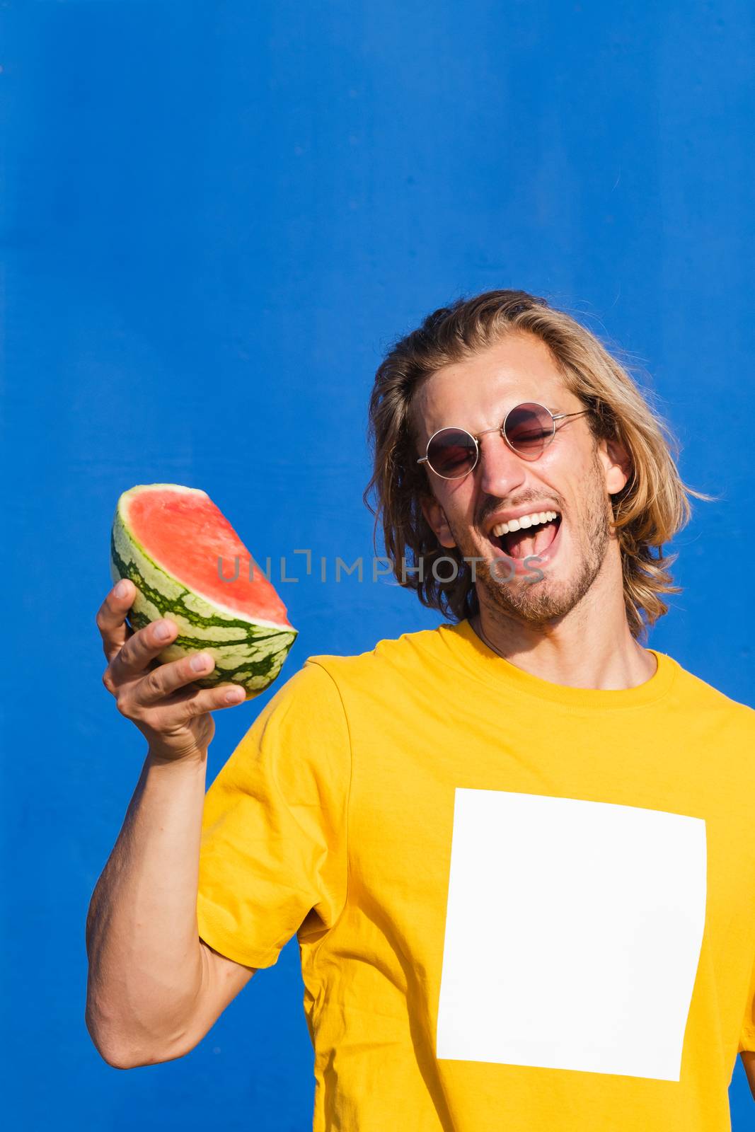 Young man with long blond hair with watermelon by Dumblinfilms