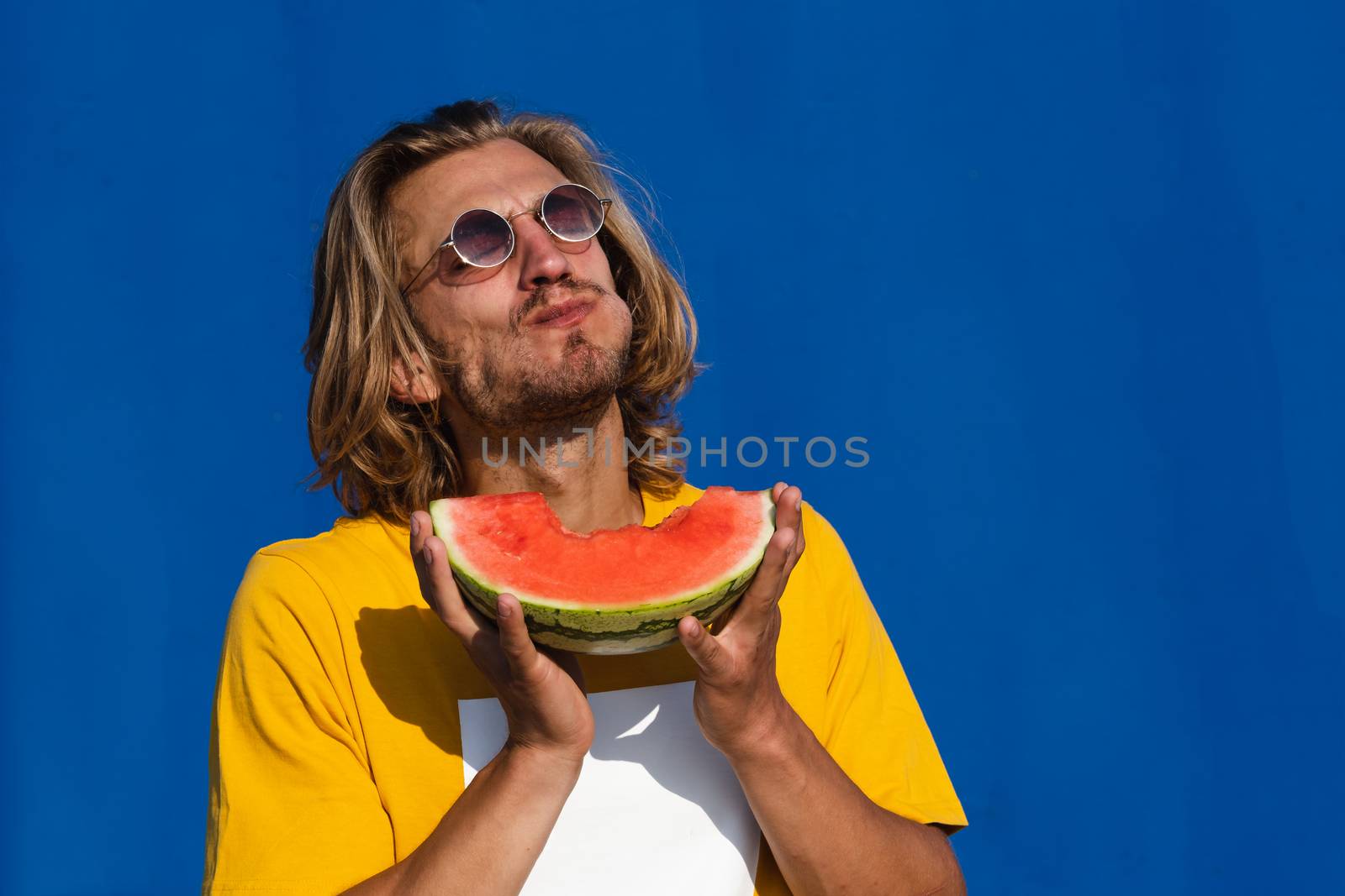 Young man with long blond hair with watermelon by Dumblinfilms