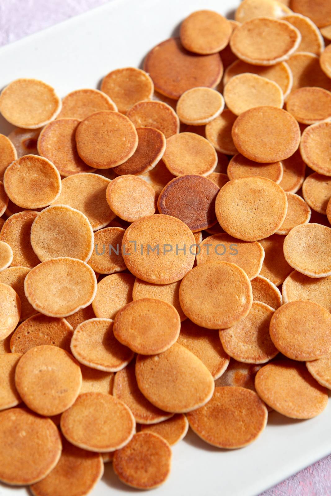 Trendy homemade breakfast, pancake cereal, mini pancakes on light plate on pink concrete background
