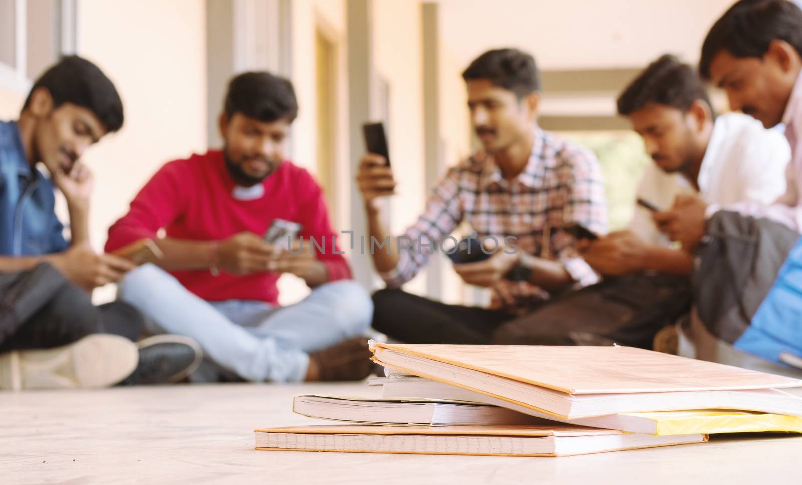 selective focus of Books, Group of students busy on mobile by avoiding books during exams at college - Teenager students on smartphone video game addiction concept