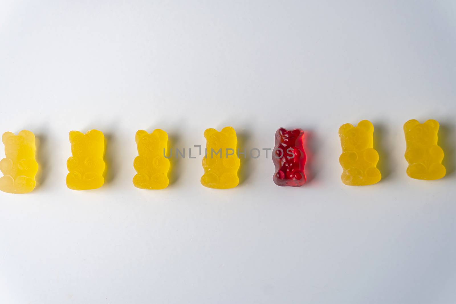 Row of yellow and red jelly bears candy on a white background.