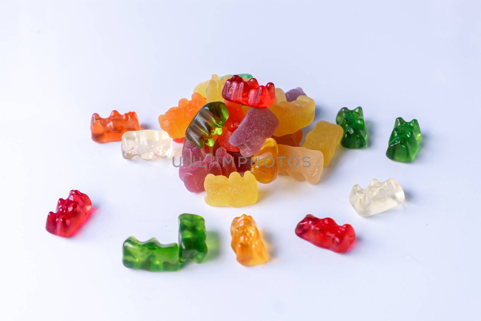 Pile of multicolored jelly bears candy on a white background.