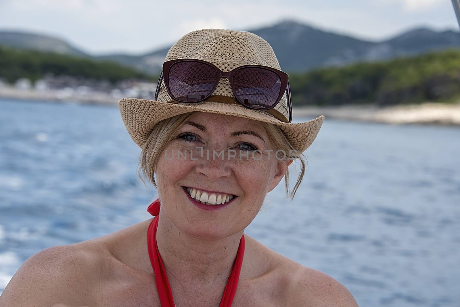 Croatia, Hvar - June 2018: Women in mid 40`s driving a small boat. She wears a straw hat and sunglassed perched on her head.