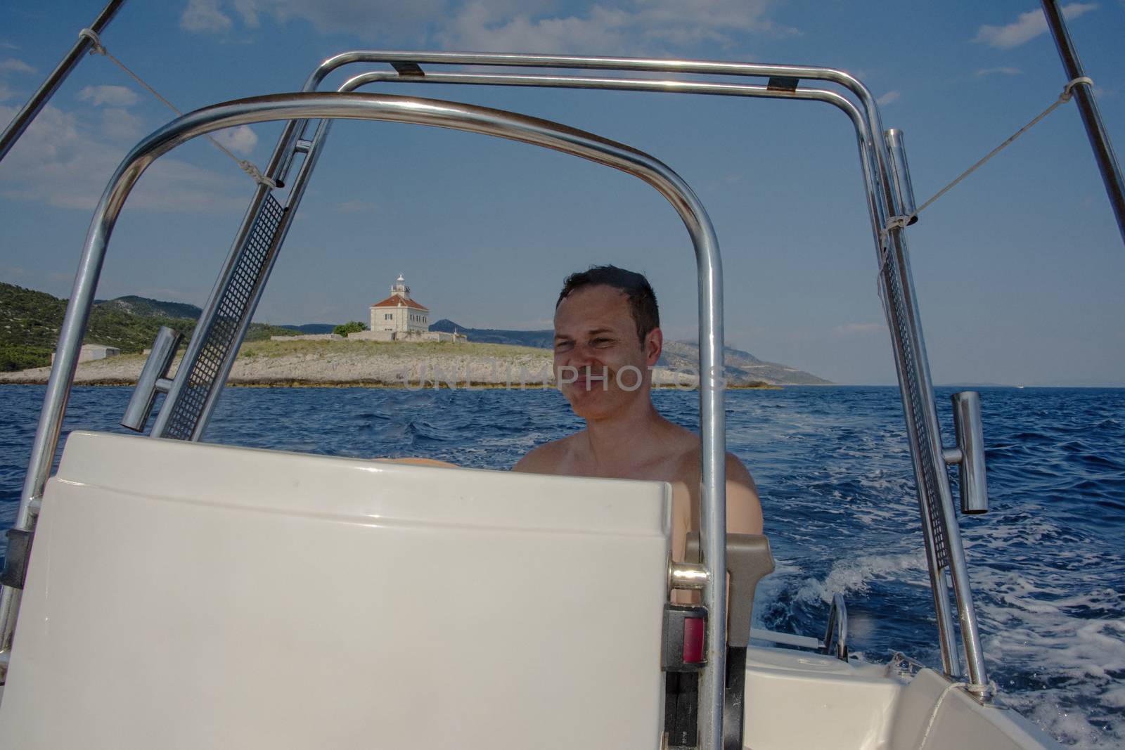 Croatia, Hvar - June 2018: Caucasian man, mid 40's drives a small boat on vacation