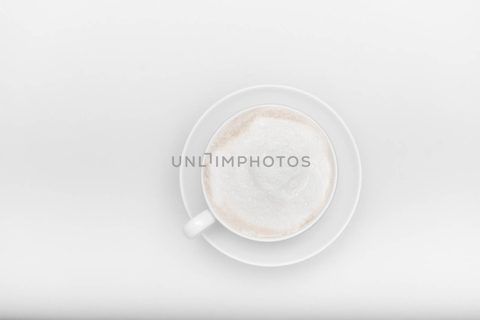 white cup with saucer and cappuccino on a white background with copyspace