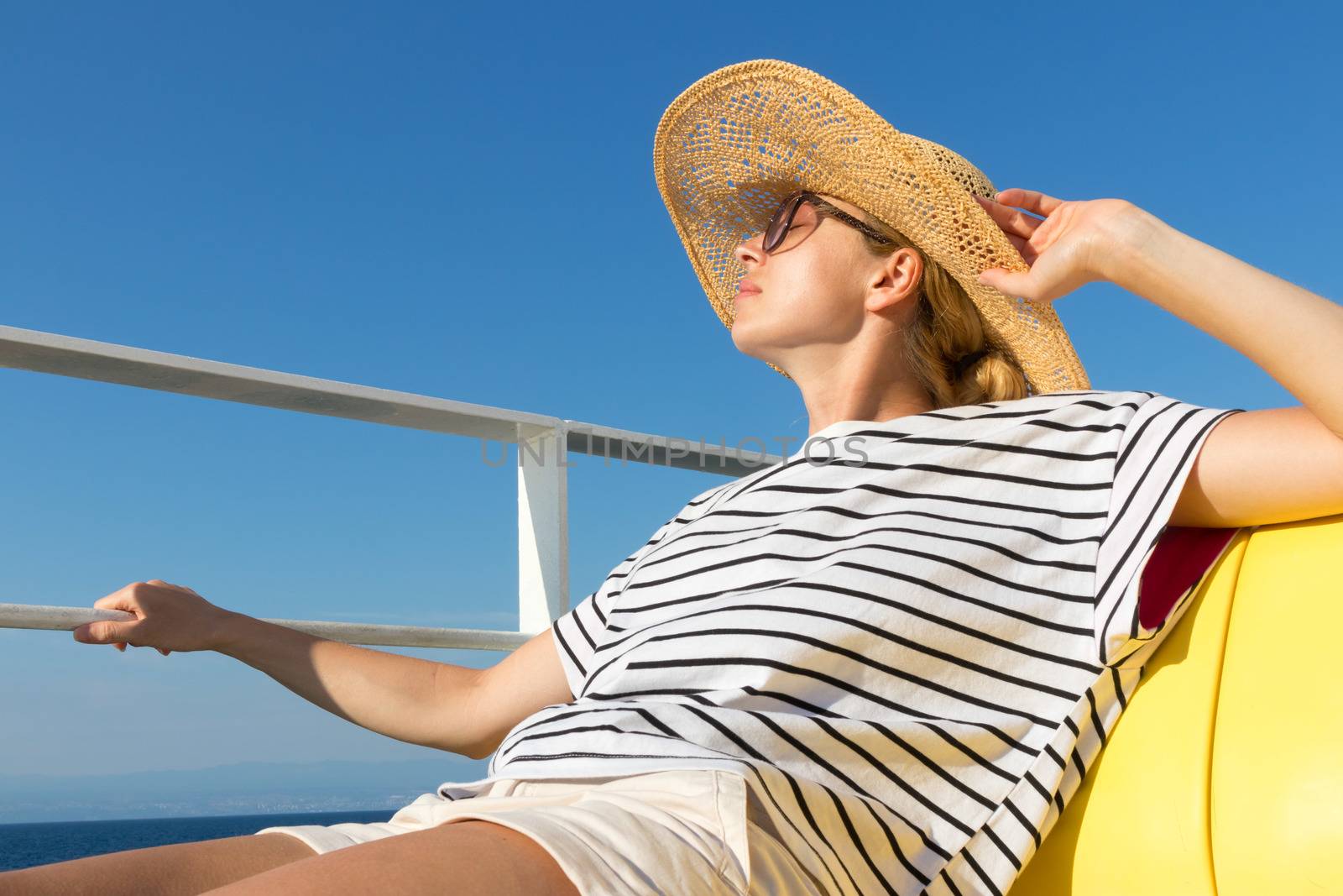 Beautiful, romantic blonde woman relaxeing on summer vacations traveling by cruse ship ferry boat. Summer vacation lifestyle.