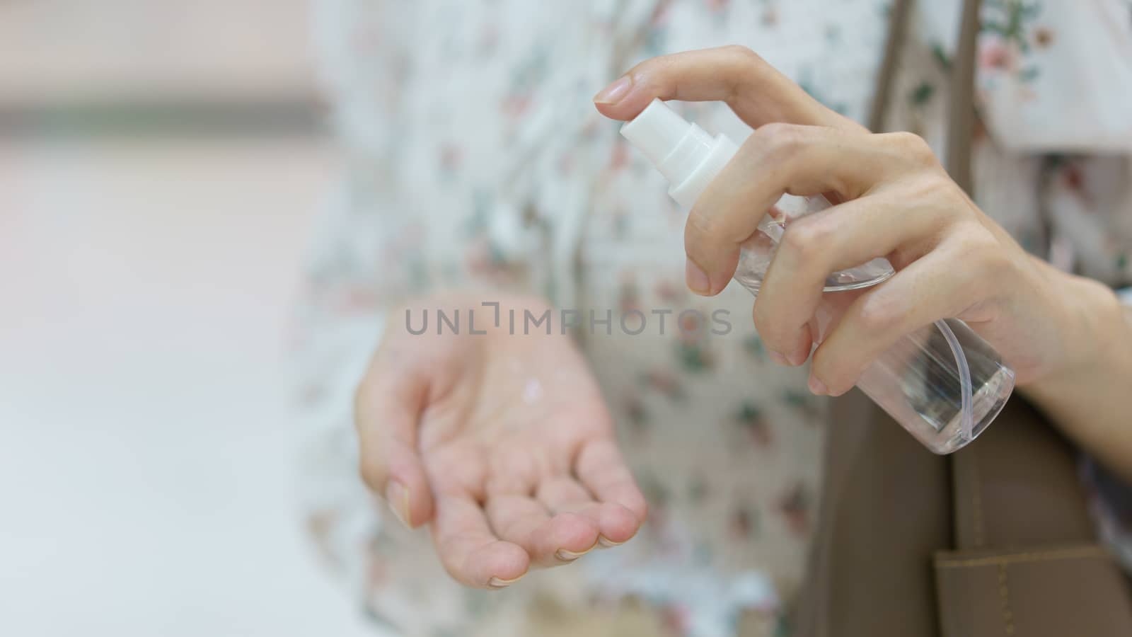 Woman using hand sanitizer spray from her hand bag, prevention of coronavirus.