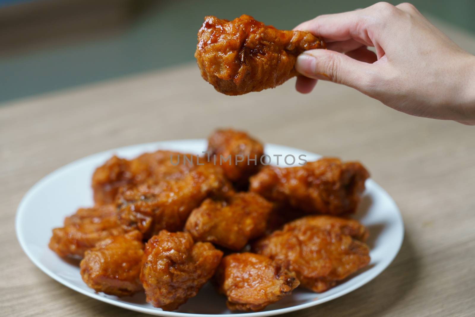Hand holding spicy deep fried chicken wings, Korean food style.