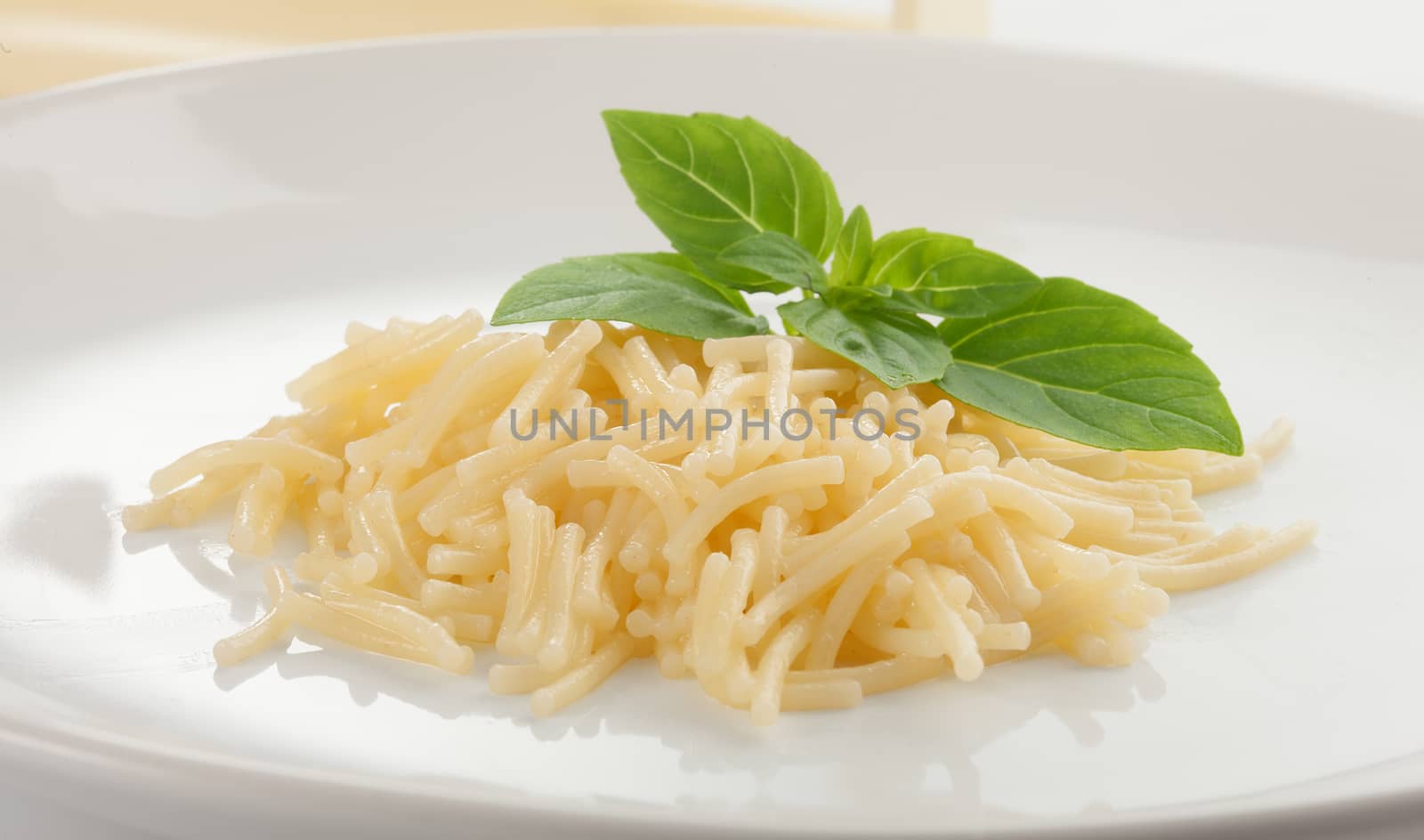 Isolated boiled vermicelli with fresh green basil on the white plate