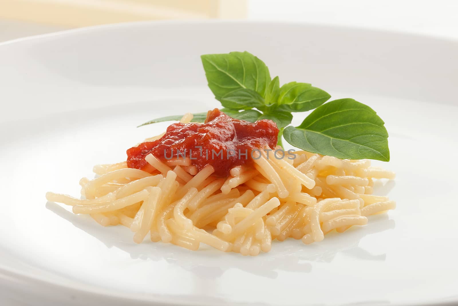 Isolated boiled vermicelli with fresh green basil on the white plate