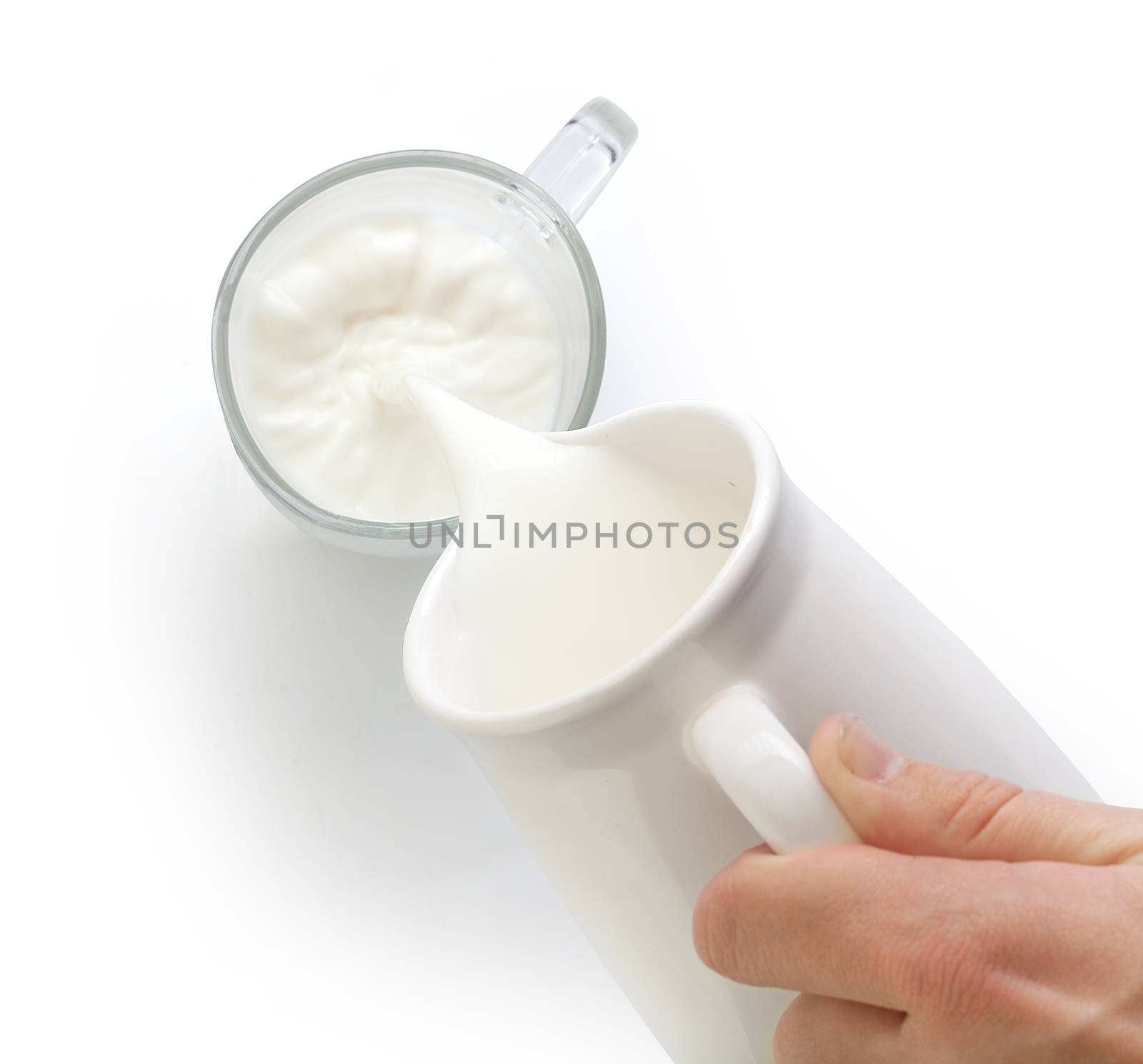 Top view of streaming milk from pitcher to glass