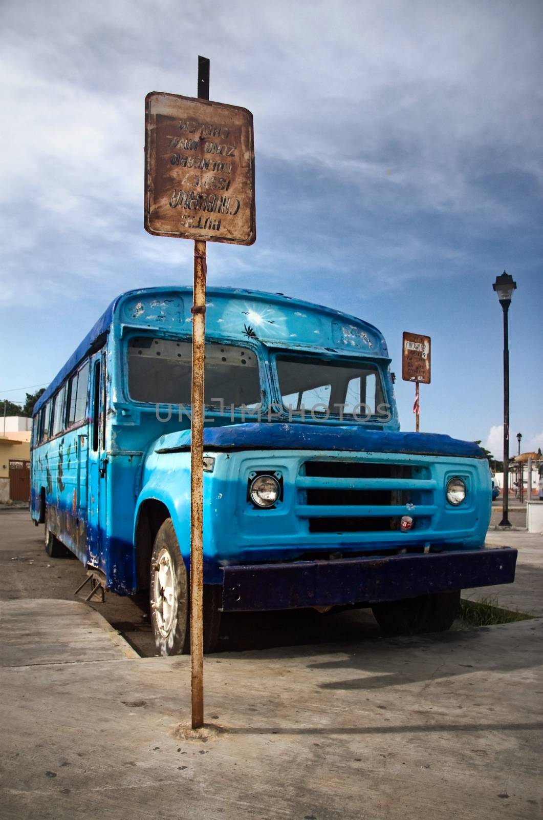 Chelem, Mexico - October 14th, 2007: Rusty old blue coach standing next to bus stop. Route: Chuburna - Isstey Spa - Chelem Naval Zone.