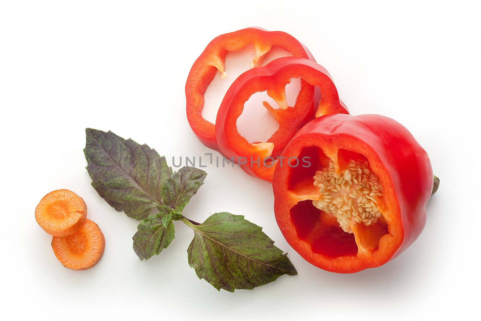 Top view of sliced red paprika, sliced carrot and branch of fresh green basil on the white background