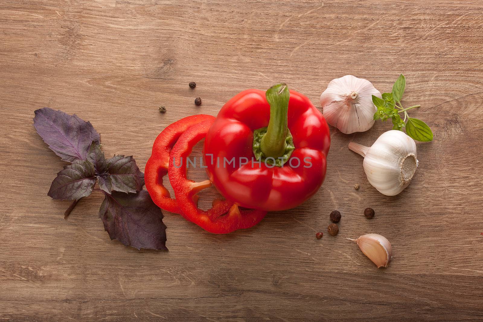 Top view of red paprika, garlic, purple basil, black pepper and oregano on the wooden table