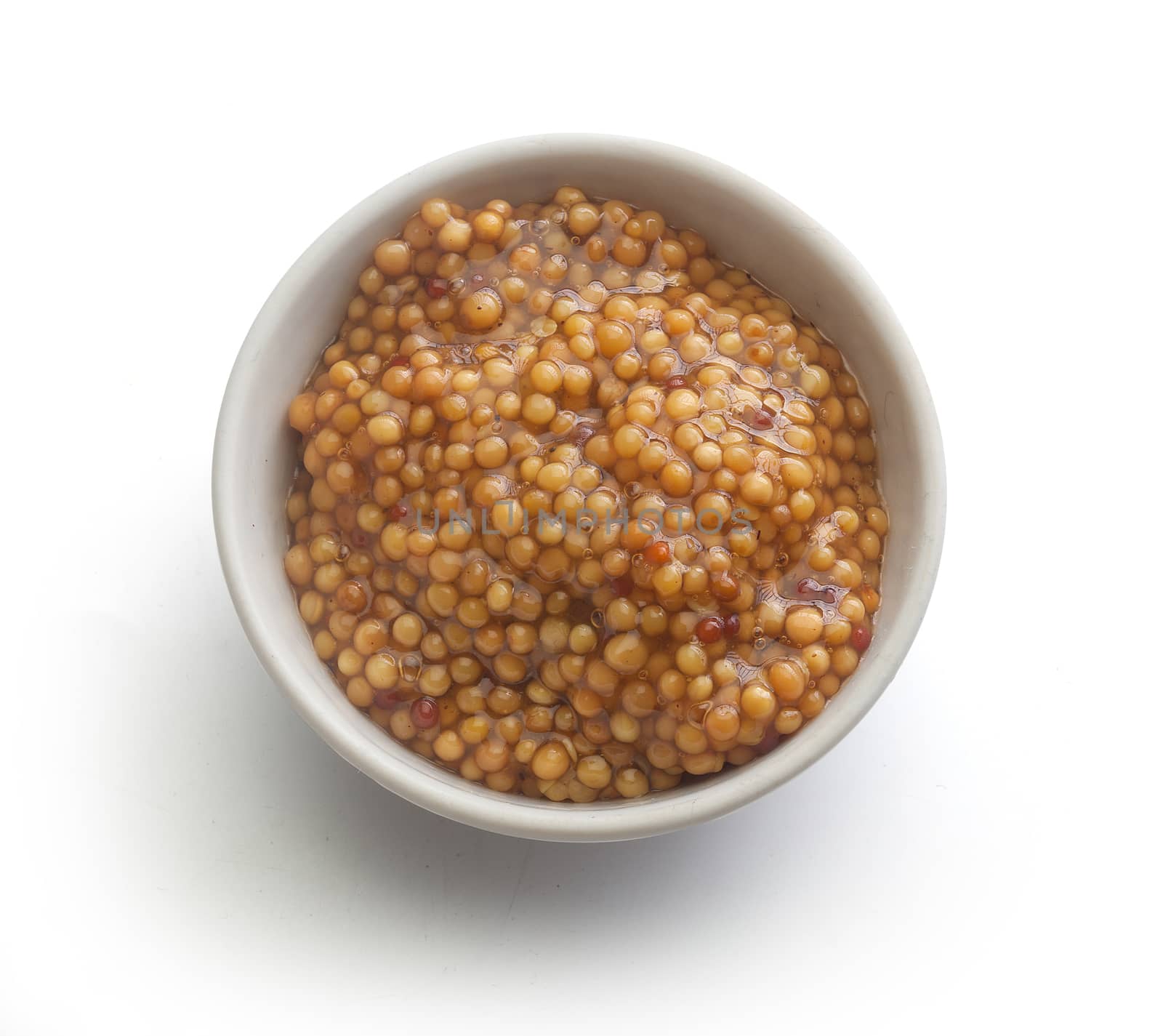 Top view of white plate with grainy mustard on the white background