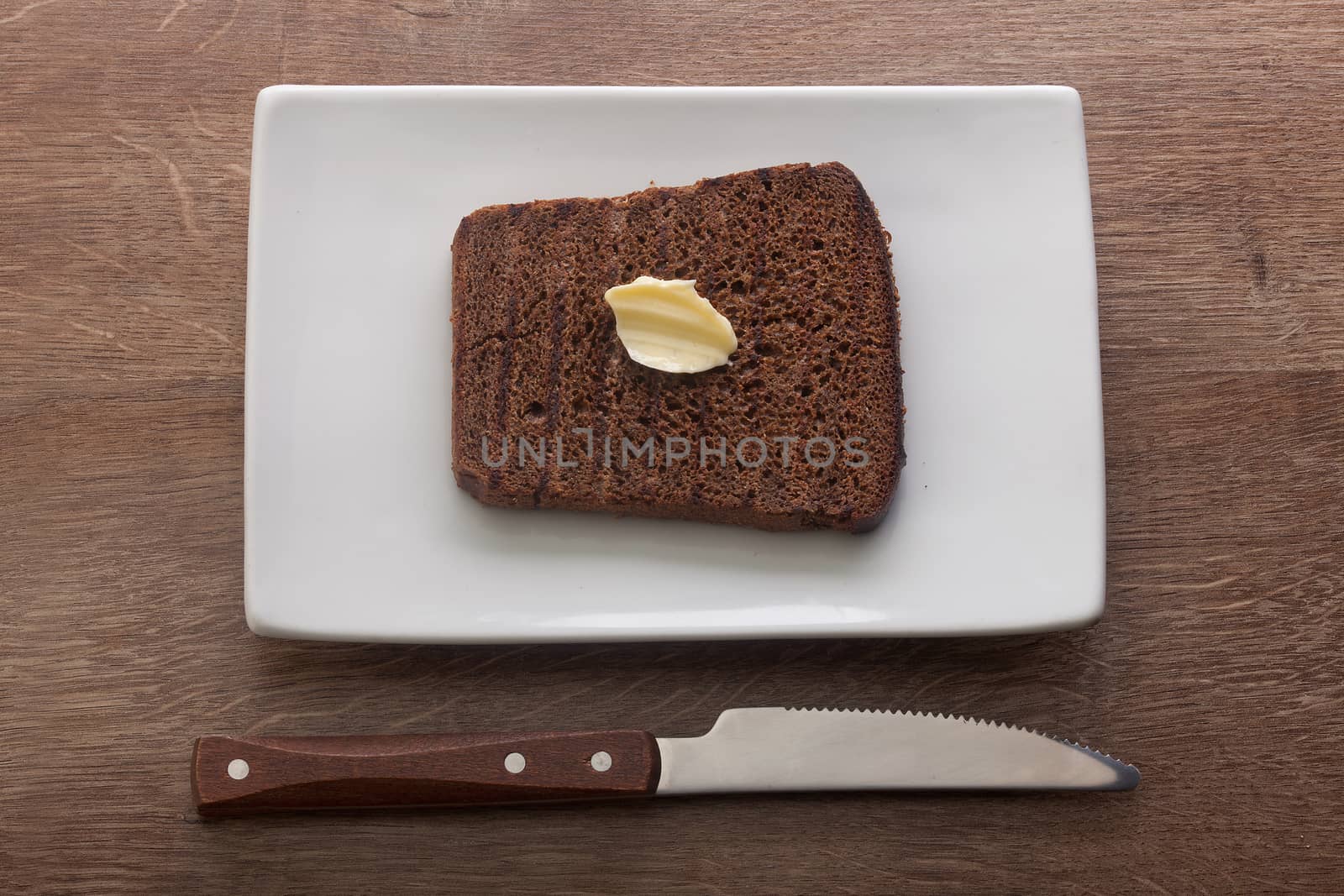 Top view of toasted custard rye bread with butter on the white plate