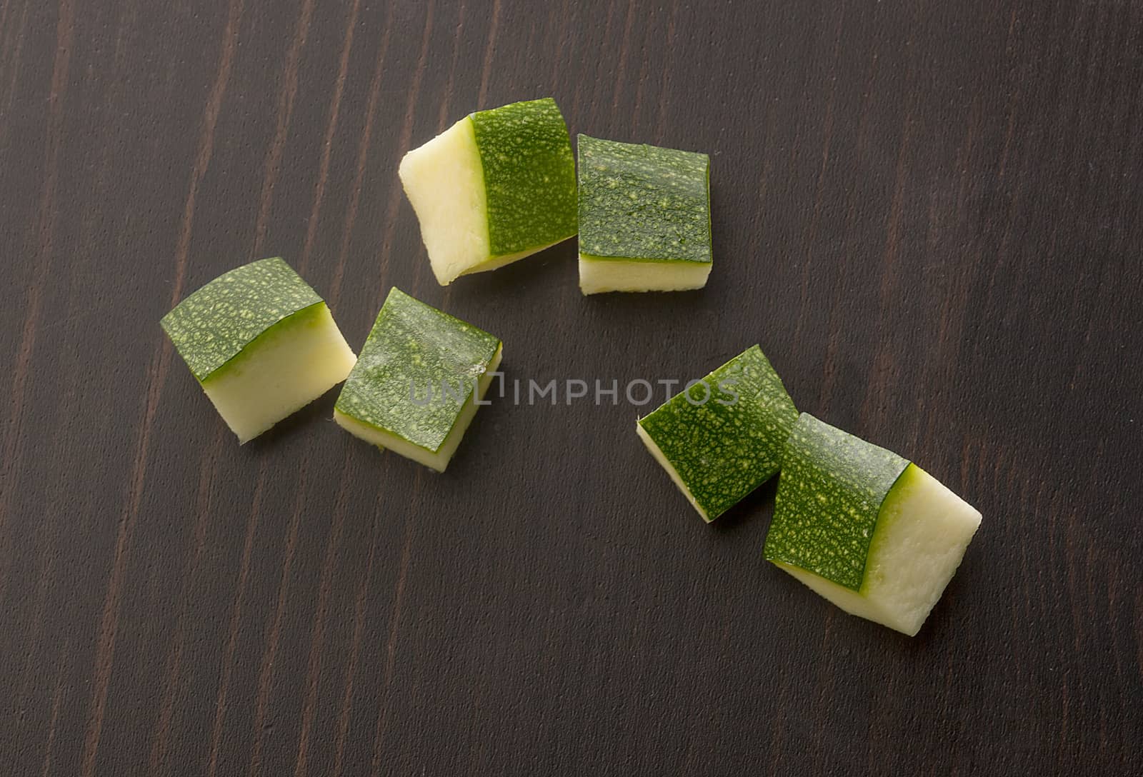 Top view of cubes of green zucchini on the black wooden table