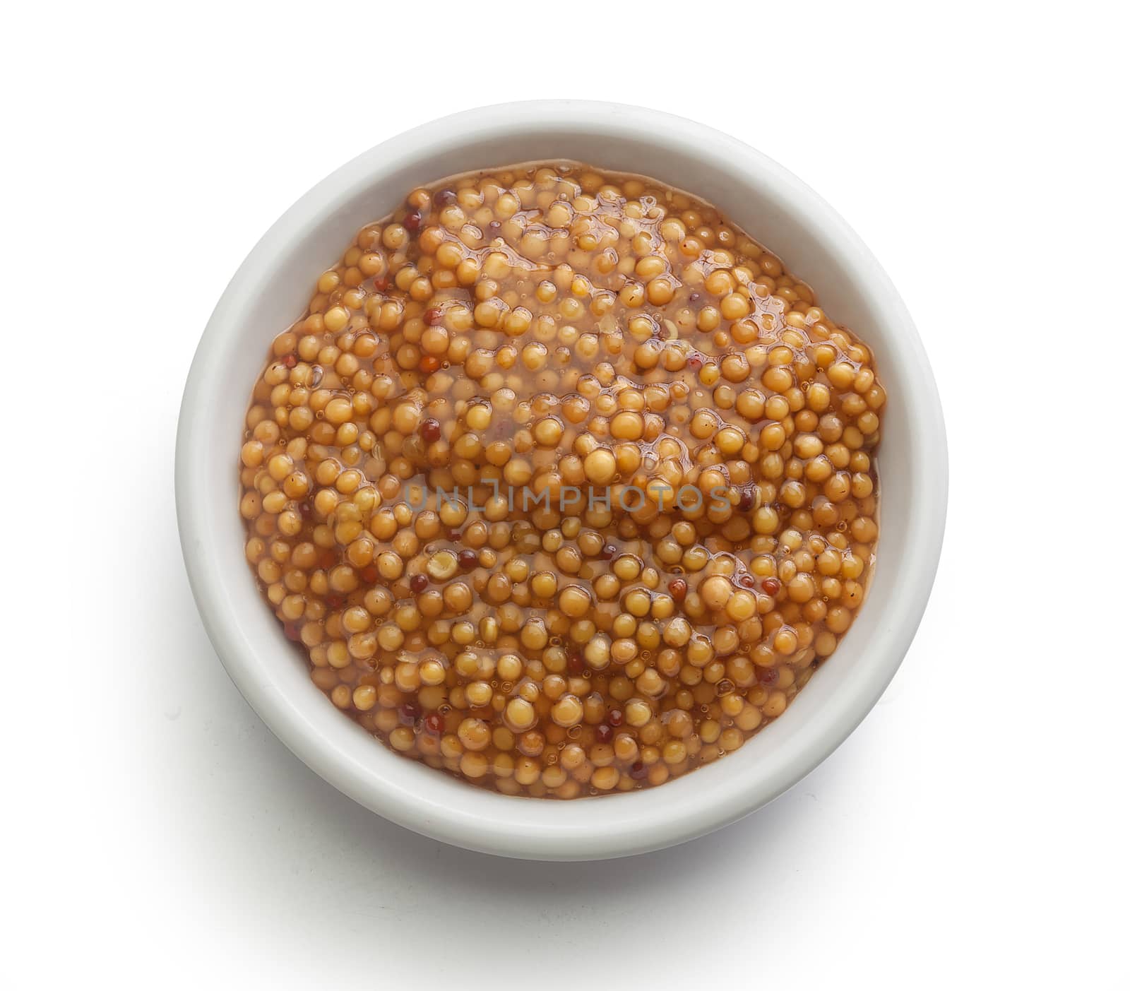 Top view of white plate with grainy mustard on the white background