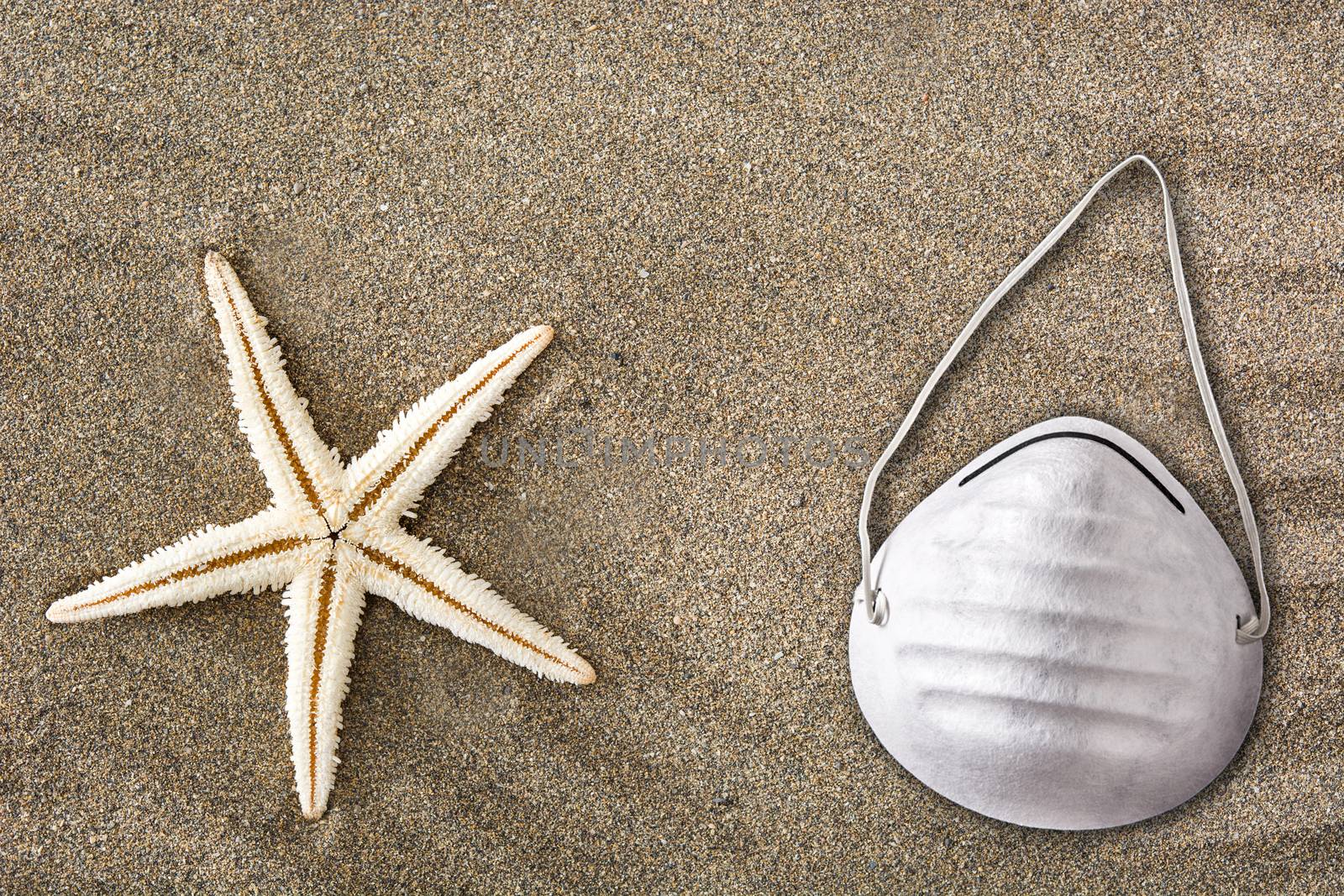 Medical protective mask and starfish on sand background