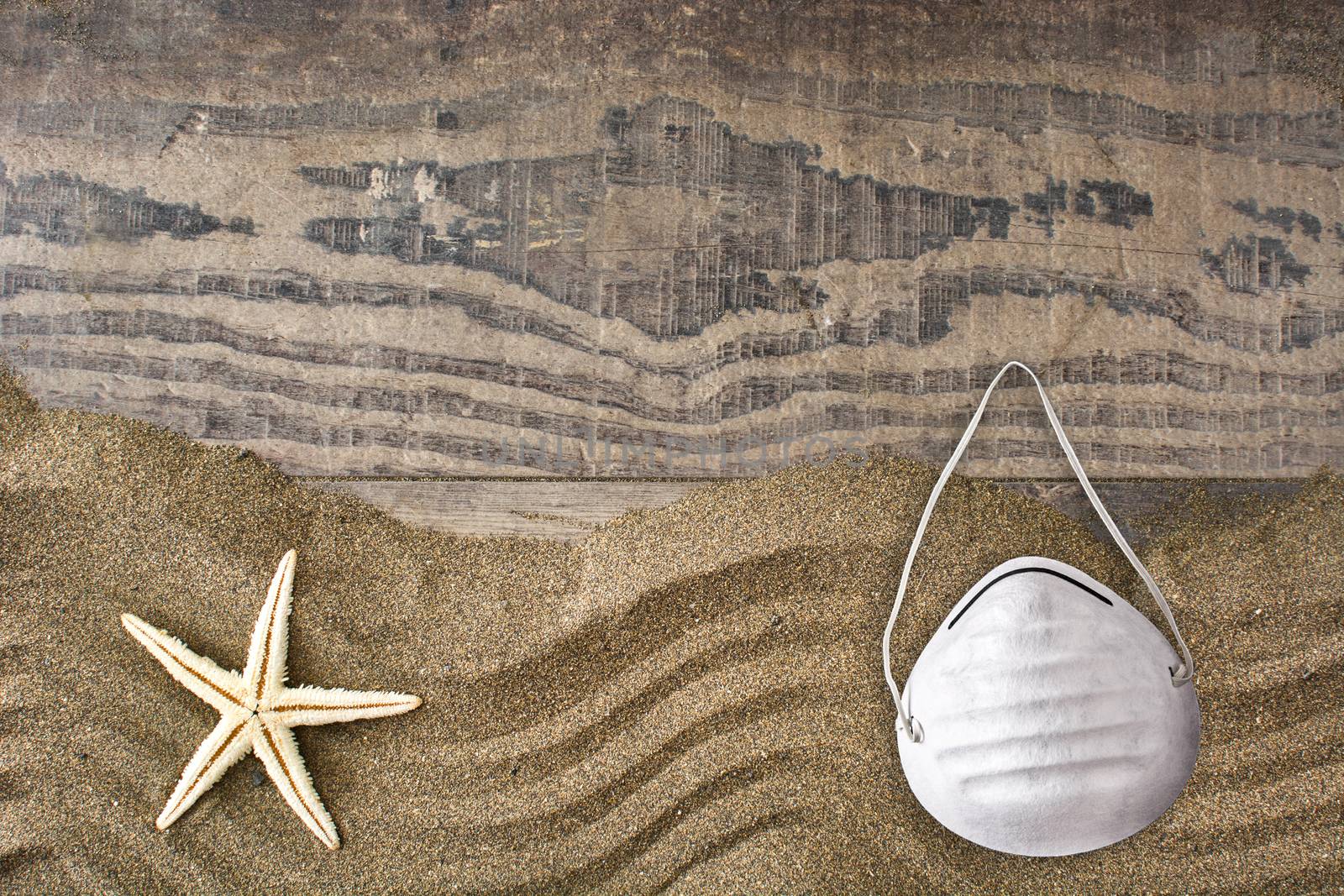 Medical protective mask and starfish on sand background