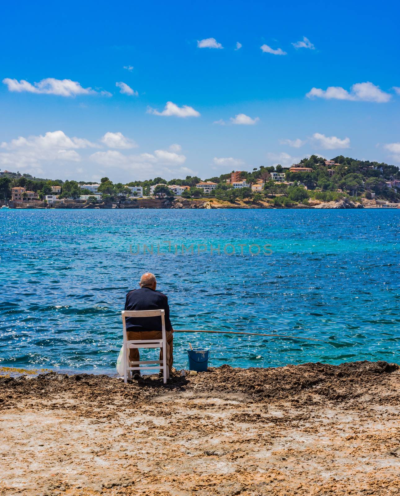 Old man is fishing at the sea by Vulcano